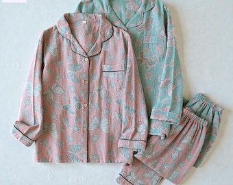 May include: Two sets of pajamas. One set is pink with a butterfly pattern, the other is teal with a butterfly pattern. Both sets include a button-down top with a breast pocket and pants. The pajamas have black trim.