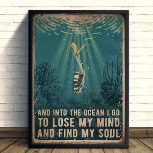 Può includere: Un poster incorniciato in stile vintage con un subacqueo sott'acqua. Il subacqueo indossa una muta a righe bianche e nere e pinne gialle. Il poster ha uno sfondo verde acqua con coralli e il testo: "AND INTO THE OCEAN I GO TO LOSE MY MIND AND FIND MY SOUL."