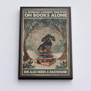 Peut inclure: Impression encadr&eacute;e avec un teckel assis sur des livres. Le texte "A Woman Cannot Survive on Books Alone, She Also Needs a Dachshund" est &eacute;crit dans une police d&eacute;corative, sur un fond de nature.
