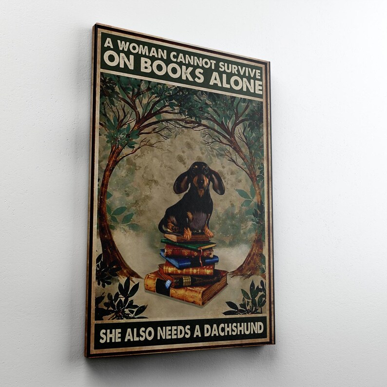 Peut inclure: Tableau encadr&eacute; avec un teckel assis sur une pile de livres. L'&oelig;uvre d'art a une esth&eacute;tique vintage et le texte se lit comme suit : "Une femme ne peut pas survivre avec les seuls livres, elle a aussi besoin d'un teckel."
