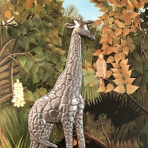 Könnte beinhalten: Eine Metall-Giraffen-Skulptur steht in einer Dschungel-Szene mit üppigem grünen Laub und blauem Himmel. Die Giraffe hat eine strukturierte Oberfläche und ist von anderen Tieren und Pflanzen umgeben. Das Kunstwerk ist von Henri Julien Rousseau signiert.