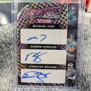 May include: A Leaf Colorful Combos Vivid football trading card featuring Michael Vick, Darren Sproles, and Donovan McNabb. The card has a colorful, patterned background and includes player signatures in blue ink. The card is encased in a clear plastic holder.