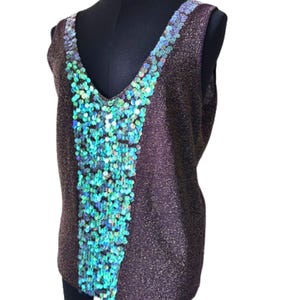 May include: A sleeveless top in a dark brown, glittery fabric featuring a deep V-neckline. A wide, vertical panel of iridescent, light-reflecting sequins in shades of teal, blue, and green runs down the center of the front of the garment.
