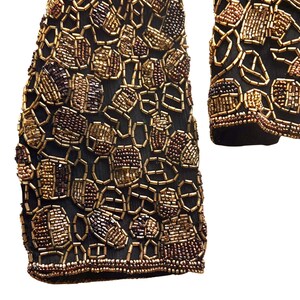 Close up of metallic gold and copper glass beads on black silk on sleeve