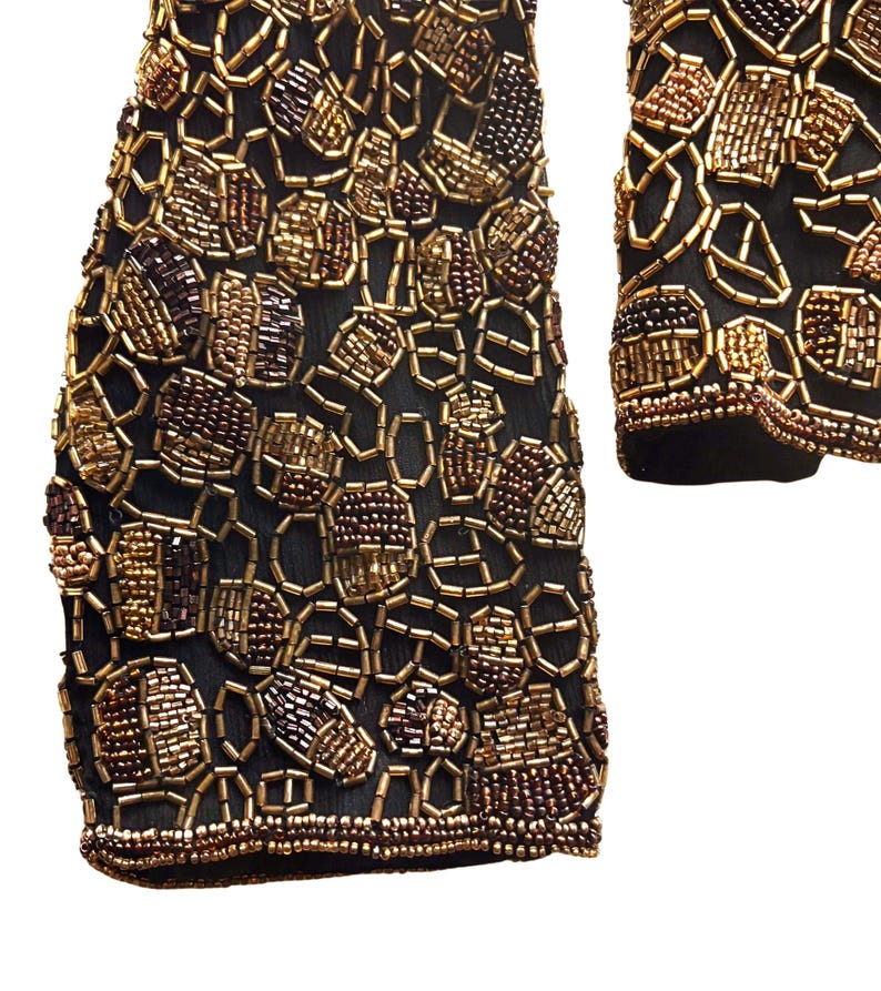 Close up of metallic gold and copper glass beads on black silk on sleeve
