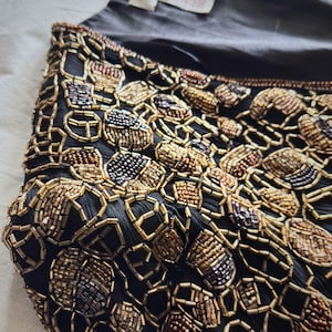 Close up of metallic gold and copper glass beads on black silk.