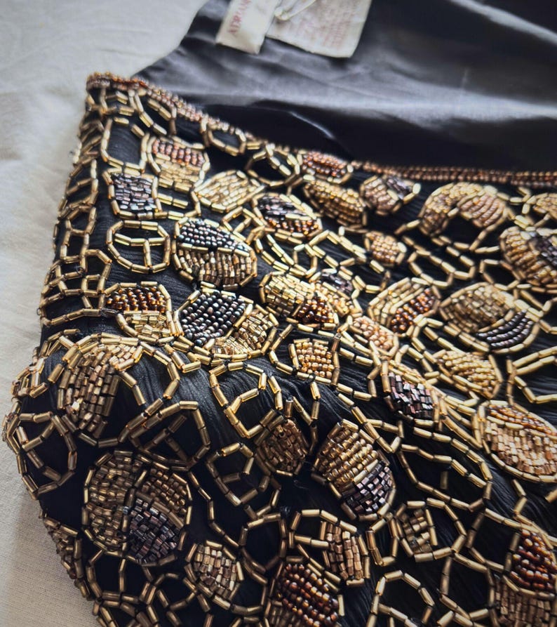 Close up of metallic gold and copper glass beads on black silk.