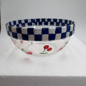 May include: A clear glass bowl with a blue and white chequered rim. The bowl features hand-painted red cherries on the sides. This decorative bowl is perfect for serving salads or displaying fruit.