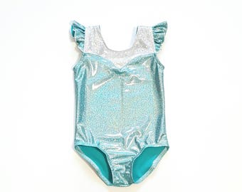 May include: A turquoise leotard with silver glitter and a white trim around the neckline. The leotard has ruffled sleeves.