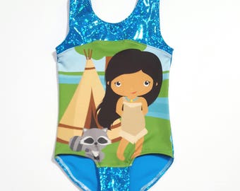 May include: A blue and green leotard with a cartoon image of a Native American girl, a teepee, and a raccoon. The leotard has a sparkly blue fabric on the top and bottom.