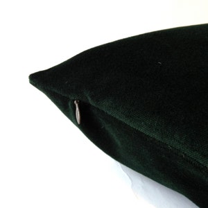 Pode incluir: Close-up de uma almofada de veludo verde escuro com fecho de correr. A almofada tem uma textura macia e felpuda e uma cor profunda e rica. O fecho de correr &eacute; de cor prateada met&aacute;lica.