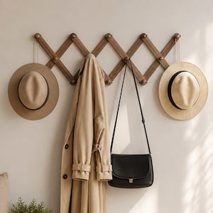 May include: An entryway with a wooden bench, cream cushion, and a wooden coat rack holding a beige coat, a black handbag, and two hats. A small potted plant and a woven basket are also present. White trainers are on the floor.