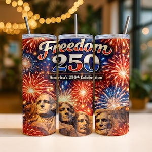 May include: Three stainless steel tumblers with straws. The tumblers feature a design celebrating America's 250th anniversary. The design includes the text "Freedom 250" with fireworks and images of Mount Rushmore.