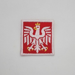 Pode incluir: Patch bordado com o emblema da Águia Branca polonesa. O patch tem um fundo vermelho com um desenho de águia branca, uma coroa amarela e garras amarelas. O patch é quadrado com uma borda rosa.