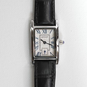 May include: A rectangular wristwatch with a silver-colored case and a black leather band. The watch face is white with blue Roman numerals and hands. The watch has a small blue gem on the side.