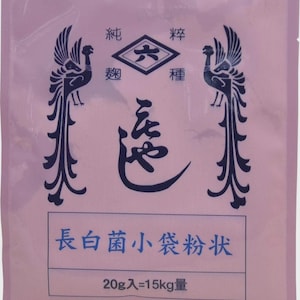 Pode incluir: Uma embalagem rosa com texto e ilustrações japonesas. Duas fénix estilizadas ladeiam a metade superior. A embalagem tem um emblema em forma de diamante e texto numa caixa retangular. O texto inferior diz "20g=15kg".