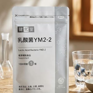 May include: A white and gray supplement packet with Japanese text, including "Lactic Acid Bacteria YM2-2" and "Supplement." A single capsule is visible. A glass of water and a small bowl are in the background.