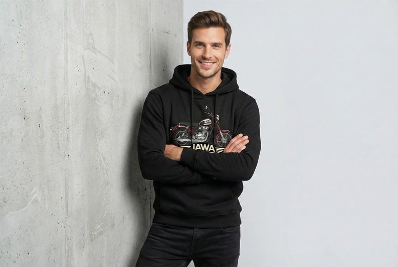 May include: Black hooded sweatshirt featuring a motorcycle graphic with the text "JAWA". The motorcycle is red and silver. The person is wearing black jeans and has their arms crossed.
