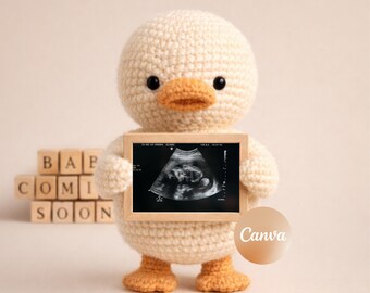 May include: A crocheted duckling holds a framed ultrasound image. The duckling is cream-colored with orange feet and beak, and black eyes. Wooden blocks behind the duckling spell out "BABY COMING SOON".