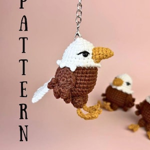 Puede incluir: Un llavero de águila hecho a mano con ganchillo, con cabeza blanca, cuerpo marrón y pico y patas amarillas. El llavero está unido a un llavero plateado. La palabra "PATTERN" está impresa verticalmente a la izquierda.