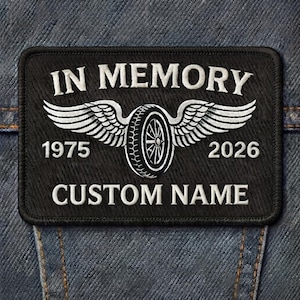 May include: A rectangular black embroidered patch featuring the white text IN MEMORY at the top and CUSTOM NAME at the bottom. In the center is a white winged tire graphic flanked by the years 1975 on the left and 2026 on the right side.