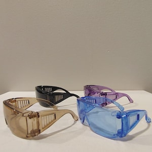 Puede incluir: Cuatro pares de gafas de seguridad en marr&oacute;n, negro, morado y azul. Cada par presenta un dise&ntilde;o envolvente con lentes transparentes y protectores laterales para la protecci&oacute;n ocular. Las gafas son de pl&aacute;stico transparente.