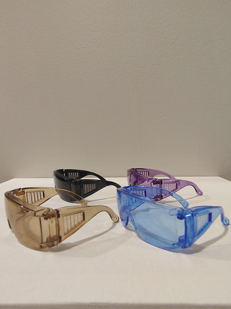 Puede incluir: Cuatro pares de gafas de seguridad en marr&oacute;n, negro, morado y azul. Cada par presenta un dise&ntilde;o envolvente con lentes transparentes y protectores laterales para la protecci&oacute;n ocular. Las gafas son de pl&aacute;stico transparente.