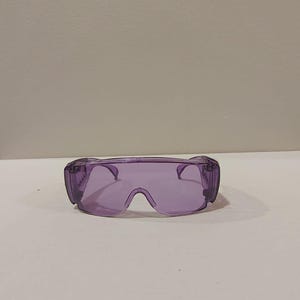 Puede incluir: Gafas de seguridad moradas con un dise&ntilde;o envolvente. Las gafas tienen una montura y lentes transparentes, que ofrecen protecci&oacute;n ocular. Dise&ntilde;adas para colocarse sobre gafas graduadas.