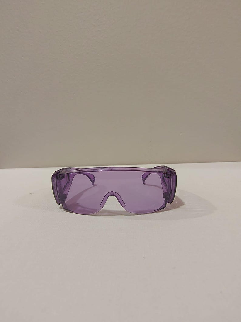 Puede incluir: Gafas de seguridad moradas con un dise&ntilde;o envolvente. Las gafas tienen una montura y lentes transparentes, que ofrecen protecci&oacute;n ocular. Dise&ntilde;adas para colocarse sobre gafas graduadas.