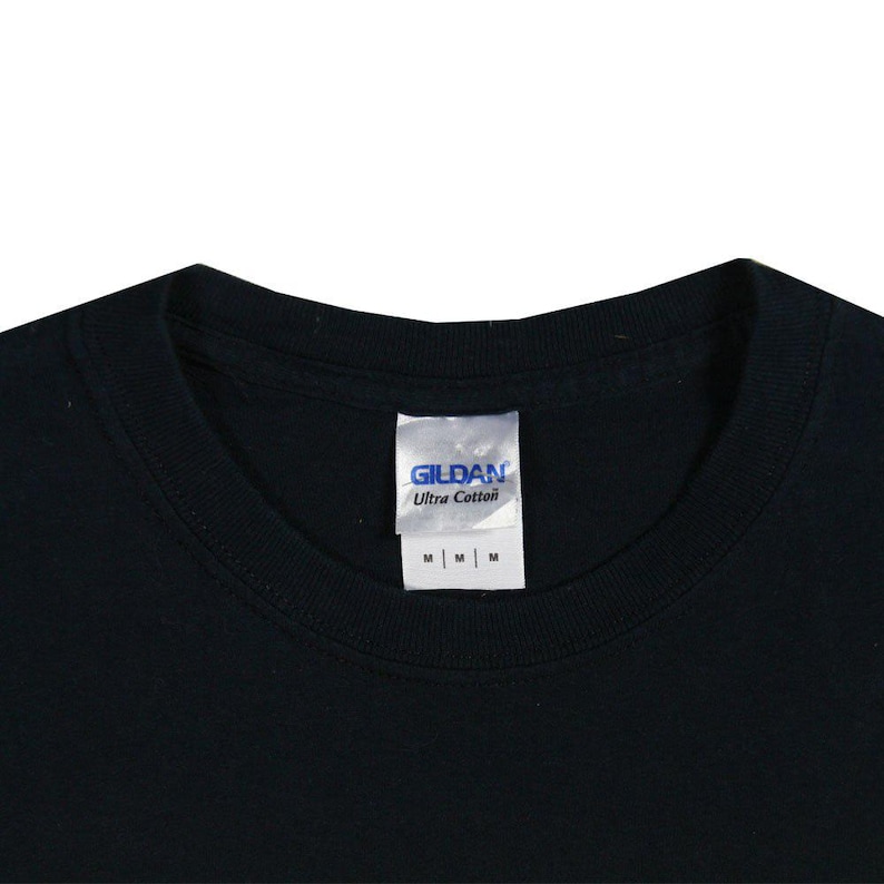 May include: Close-up of a black t-shirt collar with a white tag. The tag reads "GILDAN Ultra Cotton" and has three "M" size labels. The shirt is made of a soft, comfortable material.