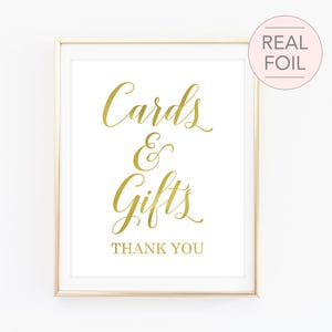 May include: Gold foil sign with the text "Cards & Gifts" and "Thank You" on a white background in a gold frame.