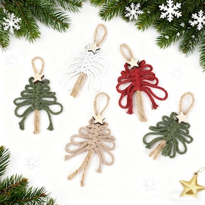 Könnte beinhalten: Fünf handgefertigte Makramee-Weihnachtsbaumschmucke in verschiedenen Farben: Grün, Weiß, Rot und Beige. Jeder Baum hat einen Holzstern und eine Juteschlaufe zum Aufhängen. Festliche Weihnachtsdekoration.