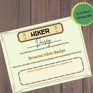 Puede incluir: Un certificado con un borde marrón y un fondo verde. El certificado dice "HIKER" y "Brownie Hiker Badge". El certificado está firmado por "Daisy".