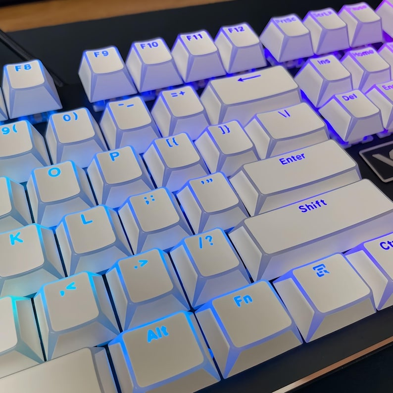 Op de afbeelding: Close-up van een wit mechanisch toetsenbord met blauwe LED-achtergrondverlichting. De toetsen zijn wit met zwarte letters. Het toetsenbord heeft een standaardindeling met functietoetsen, numerieke toetsen en pijltjestoetsen.