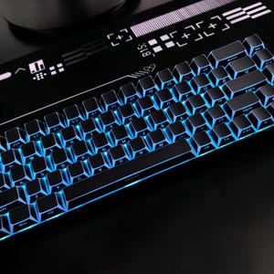 May include: A black mechanical keyboard with blue LED backlighting. The keyboard has a compact design with black keycaps and a sleek, modern aesthetic. The keys are illuminated with a vibrant blue glow. The keyboard is designed for gaming and typing.