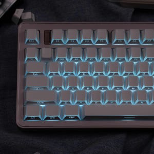 May include: A mechanical keyboard with white keycaps and blue backlighting. The keyboard has a gray frame and a brown keycap in the top row. The keys are labeled with letters, numbers, and symbols. The keyboard is designed for computer use.