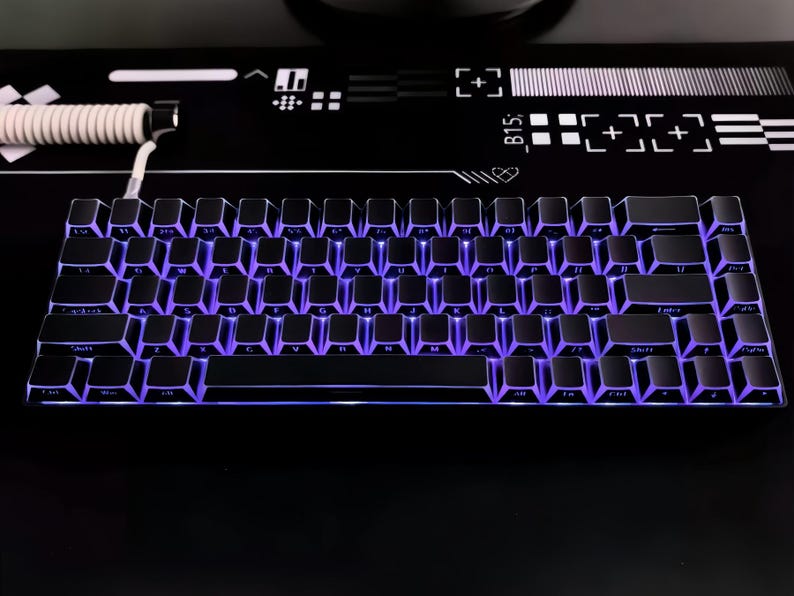 May include: A black mechanical keyboard with purple LED backlighting. The keyboard has a compact layout with a white coiled cable. The keyboard is on a black surface with white graphic designs.
