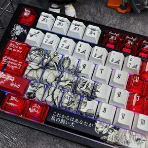 May include: Custom mechanical keyboard with a black frame and a variety of keycaps. The keycaps feature a mix of white, red, and clear designs, including floral patterns and Japanese text. Some keys have symbols and numbers.