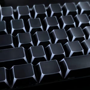 May include: Close-up of a mechanical keyboard with black keycaps and white illuminated edges. The keys are arranged in a grid pattern, highlighting the square shape. A computer accessory.