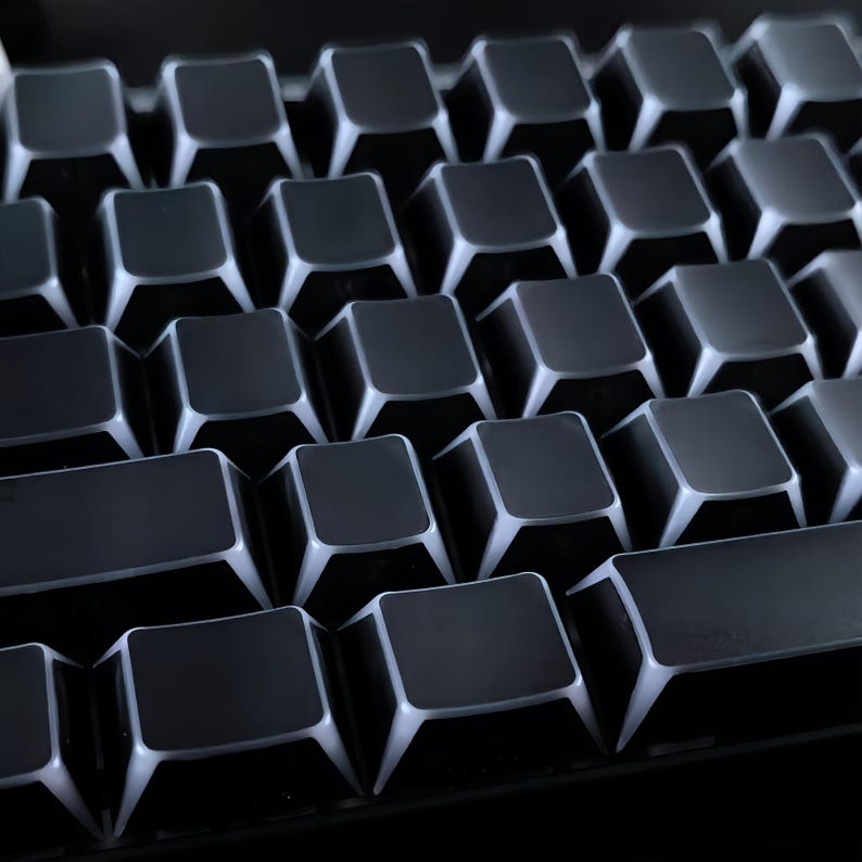 May include: Close-up of a mechanical keyboard with black keycaps and white illuminated edges. The keys are arranged in a grid pattern, highlighting the square shape. A computer accessory.