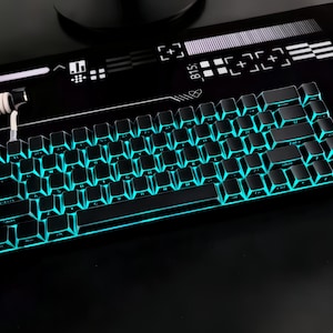 May include: A black mechanical keyboard with teal backlighting. The keyboard is on a black surface with a white and black design. The keys are dark, and the teal light shines through the keycaps.