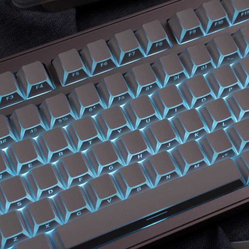 May include: A close-up of a mechanical keyboard with white keycaps and blue backlighting. The keyboard has a standard QWERTY layout with function keys and number keys. The keycaps are evenly spaced and the lighting is bright.