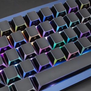 May include: A close-up of a mechanical keyboard with grey keycaps. The keys are illuminated with a rainbow of colours, creating a vibrant glow. The keyboard has a compact layout, with letters and numbers visible on the keys.