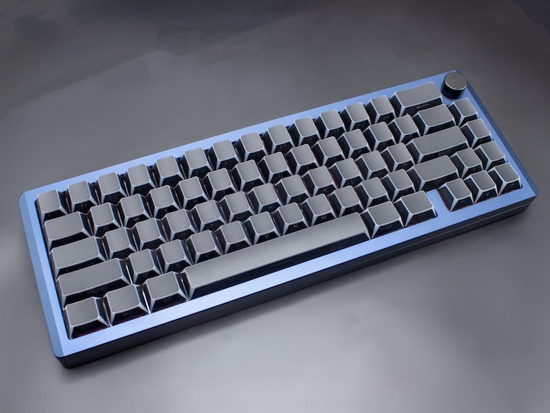 May include: A mechanical keyboard with a blue frame and dark grey keycaps. The keyboard has a compact layout, with a knob in the upper right corner. The keys are arranged in a standard QWERTY layout.