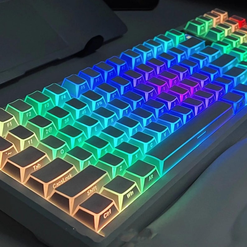 May include: A white mechanical keyboard with backlit keys displaying a rainbow of colors. The keys are arranged in a standard layout, with function keys, alphanumeric keys, and modifier keys visible. The keyboard is angled slightly upward.