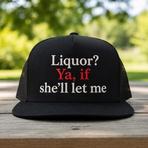 May include: Black trucker hat with the text "Liquor? Ya, if she'll let me" embroidered in white and red. The hat has a mesh back and a curved brim. The hat is sitting on a wooden surface.