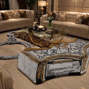 May include: A large, irregularly shaped area rug featuring a detailed, textured design inspired by a Norse hammer. The rug incorporates shades of grey, black, and gold, with intricate black line patterns and symbols woven into the surface.