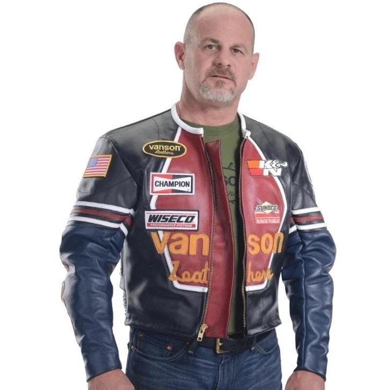 Peut inclure: Veste de moto en cuir noir, bleu et rouge avec plusieurs &eacute;cussons et inscriptions. La veste pr&eacute;sente un &eacute;cusson du drapeau am&eacute;ricain, les textes "CHAMPION", "WISECO" et "Van Leather". Elle a une fermeture &eacute;clair et un col blanc.