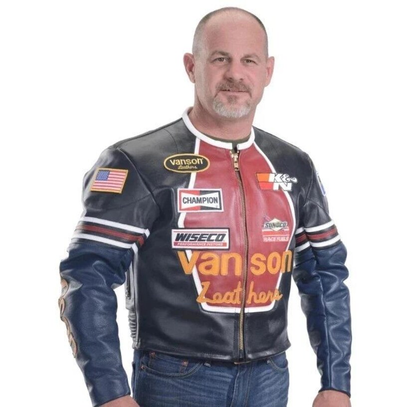 Peut inclure: Veste de moto en cuir noir et bleu avec des d&eacute;tails rouges et blancs. Comprend des &eacute;cussons avec les textes "Champion", "Wiseco", "Sunoco" et "Vanson Leathers". Un &eacute;cusson du drapeau am&eacute;ricain est sur la manche gauche.