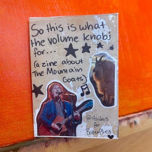 May include: A handmade zine with the text "So this is what the volume knobs for... (a zine about The Mountain Goats)". The zine features a photo of a musician playing a guitar, a goat, and musical notes.